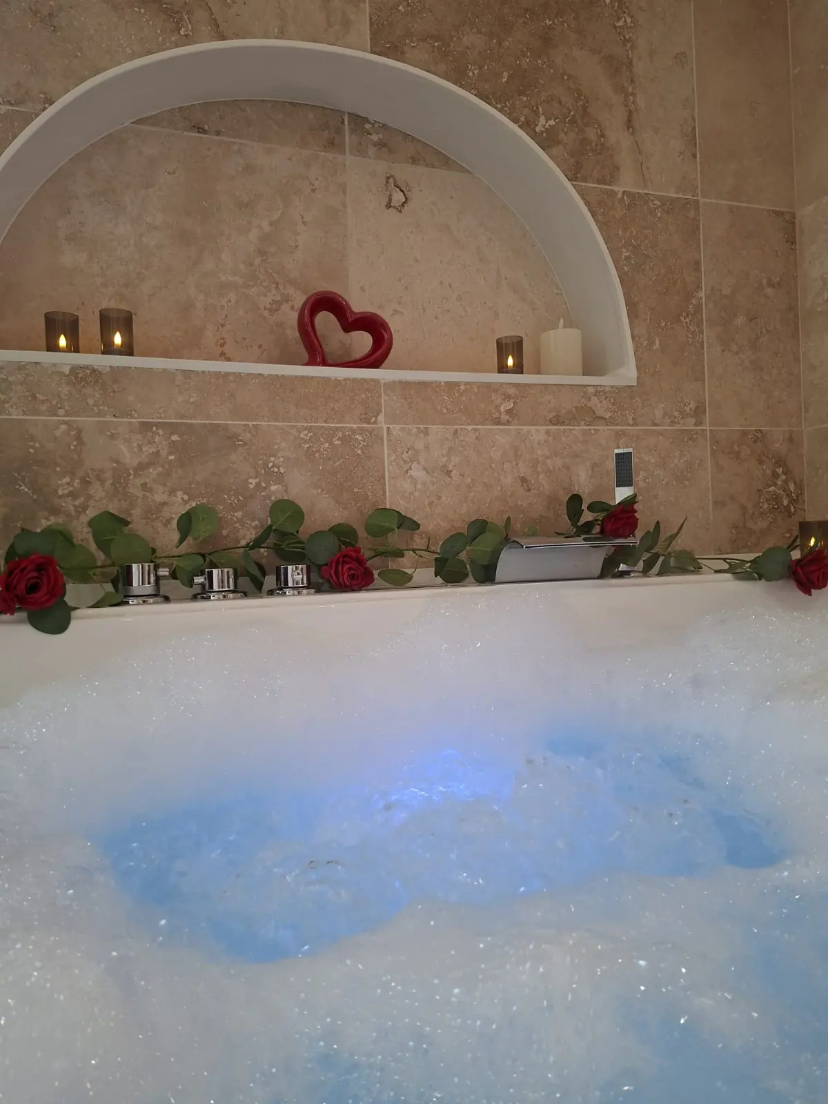 Baignoire balnéo en mousse décorée de roses rouges et d'eucalyptus