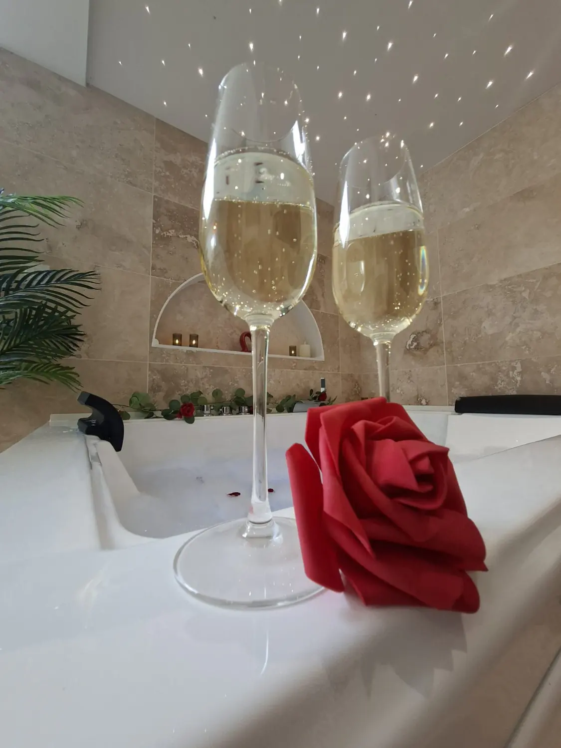 Deux coupes de champagne et une rose rouge posées au bord du bain à remous
